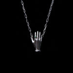 Necklace in sterling silver featuring a hand adorned with emerald