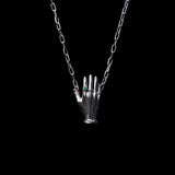 Necklace in sterling silver featuring a hand adorned with emerald